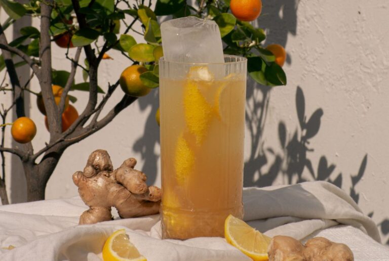 Rompe Mar Chilcano cocktail with ginger and lemon garnish on a white tablecloth with an orange tree and white wall in the background