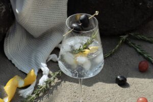Rompe Mar Pisco & Tonic cocktail with olives and garnish on a rock by the beach