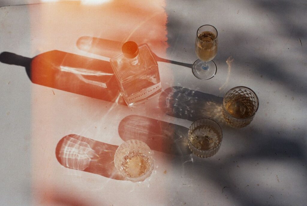 Bird's eye view of Rompe Mar Pisco bottle and four glasses with lens flare effect